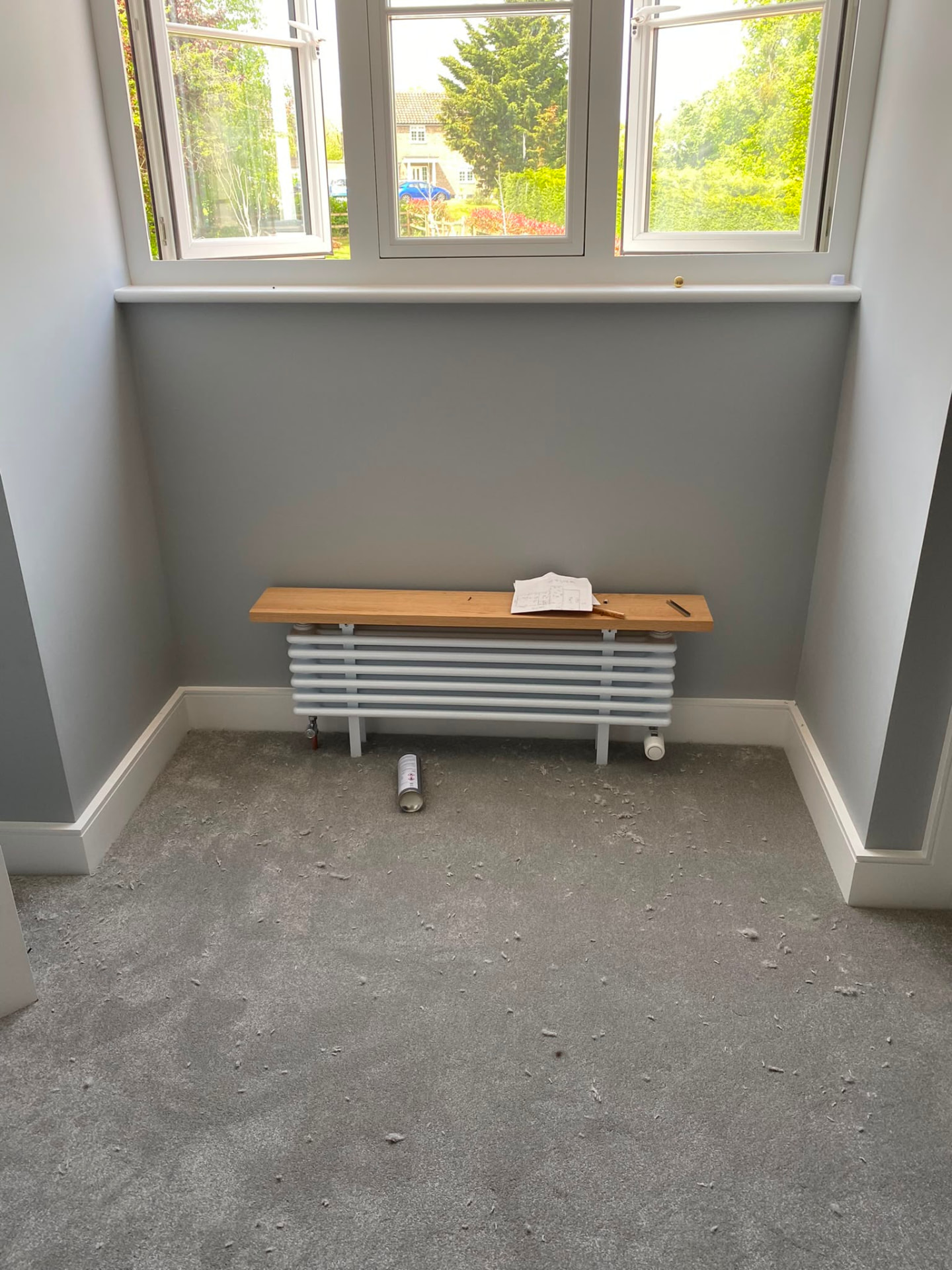 Horizontal white column radiator installation with oak shelf in a bay window, fitted by Gas Safe registered engineers in Essex