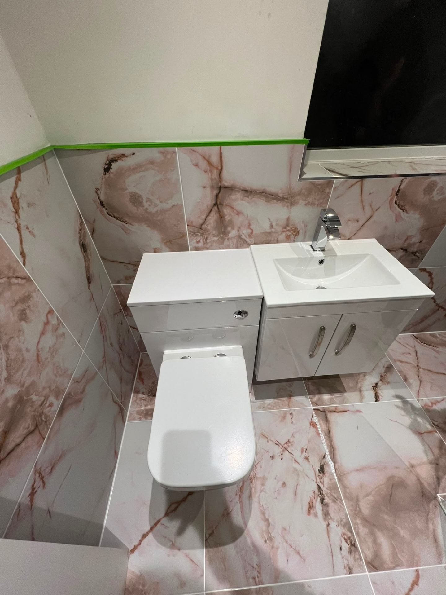 Bathroom fitting with new WC and vanity unit against marble-effect tiling, fitted by Gas Safe registered engineers in Essex