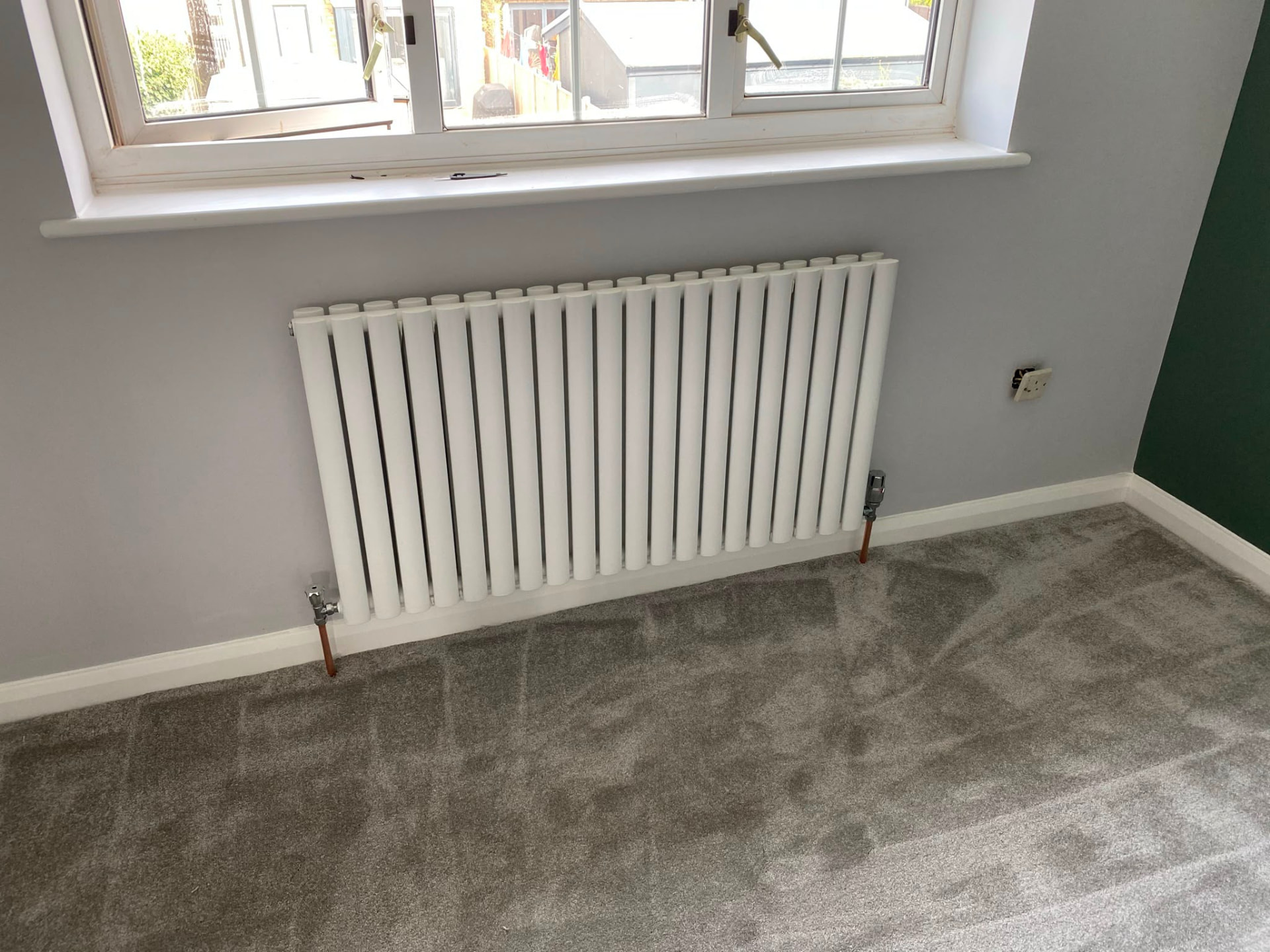 Horizontal oval column radiator installation fitted under a bedroom window, fitted by Gas Safe registered engineers in Essex